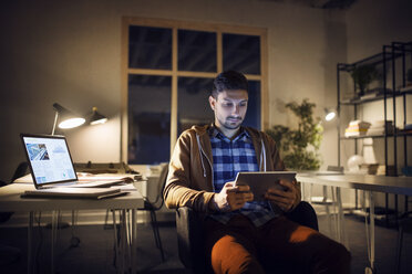 Mann studiert mit Tablet-Computer in der Bibliothek bei Nacht - CAVF45034