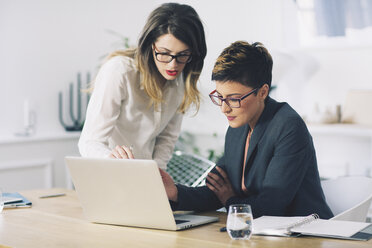 Geschäftsfrauen diskutieren bei der Benutzung eines Laptops im Büro - CAVF45065