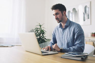 Businessman using laptop computer at desk in office - CAVF45068