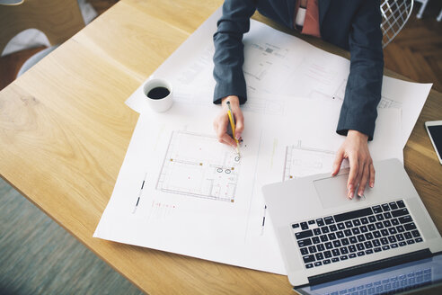 Cropped image of businesswoman analyzing blueprint at table - CAVF45084