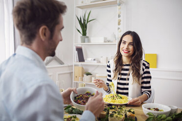 Glückliche Frau isst Spaghetti, während sie einen Freund beim Mittagessen ansieht - CAVF45117