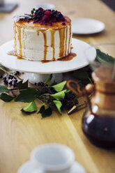 Close-up of cake on stand at wooden table - CAVF45122