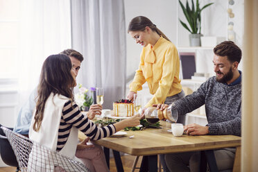 Smiling woman cutting cake while friends sitting at dinning table in party - CAVF45124