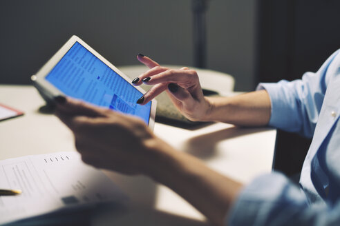 Beschnittenes Bild einer Geschäftsfrau, die einen Tablet-Computer benutzt, während sie am Schreibtisch sitzt - CAVF45141