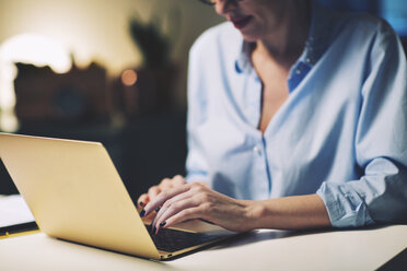 Mittelteil einer Geschäftsfrau, die einen Laptop benutzt, während sie im Heimbüro sitzt - CAVF45150