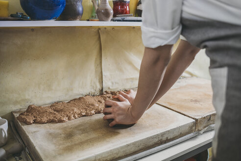 Midsection of female potter kneading clay on table in workshop - CAVF45155