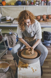 High angle view of confident potter molding shape to clay in workshop - CAVF45165