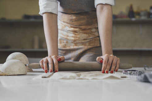 Midsection of female potter rolling clay on table in workshop - CAVF45179