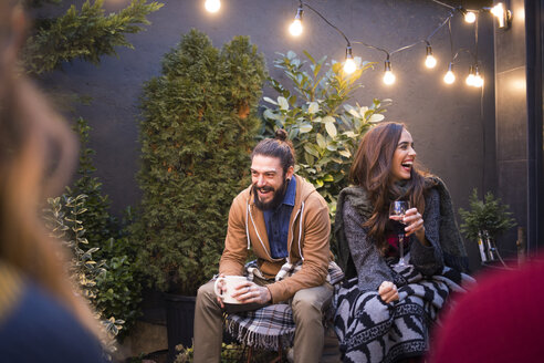 Cheerful friends enjoying drinks while sitting in backyard - CAVF45189