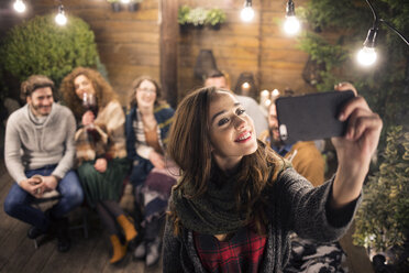 Frau nimmt Selfie mit Freunden im Hinterhof bei Nacht - CAVF45214