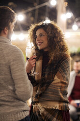 Frau mit Wein im Gespräch mit männlichem Freund im Hinterhof bei Nacht - CAVF45218