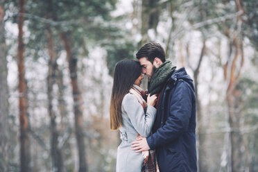 Couple romancing while standing in forest during winter - CAVF45236