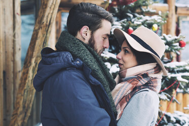 Romantic couple looking at each other while standing by Christmas tree - CAVF45239