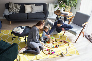 High angle view of parents looking at son playing with toy train at home - CAVF45245