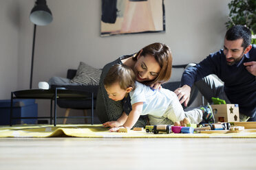 Eltern und Sohn spielen mit Spielzeugeisenbahn zu Hause - CAVF45246