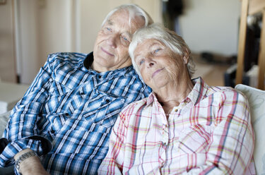 Älteres Paar entspannt sich gemeinsam auf dem Sofa im Wohnzimmer - MASF06490