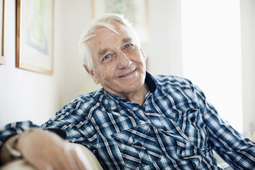 Porträt eines lächelnden älteren Mannes, der im Wohnzimmer sitzt - MASF06513