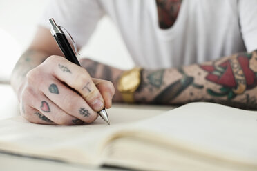 Midsection of a tattooed man writing - MASF06538