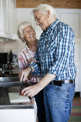 Happy senior couple preparing food together - MASF06555