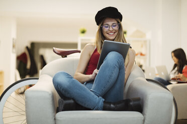 Lässige junge Frau, die ein Tablet im Coworking Space benutzt - OCAF00216