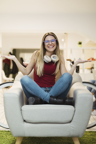 Glückliche junge Frau, die in einem Sessel im Coworking Space sitzt, lizenzfreies Stockfoto