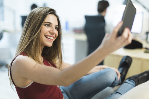 Smiling young woman using cell phone in the office - OCAF00225
