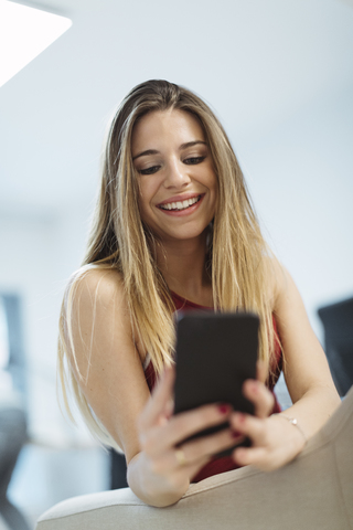 Smiling young woman using cell phone in the office stock photo