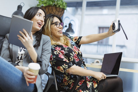 Two happy young women in the office taking a selfie stock photo