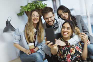 Happy casual coworkers in the office taking a selfie - OCAF00241