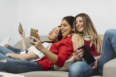 Fröhliche, lässige junge Frauen im Büro, die Handys benutzen - OCAF00243