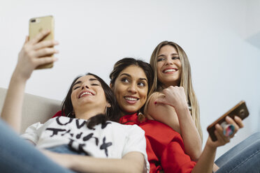 Fröhliche, lässige junge Frauen im Büro, die Handys benutzen - OCAF00244