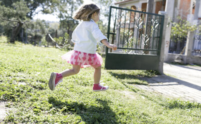 Little girl running on meadow in the garden - KMKF00213