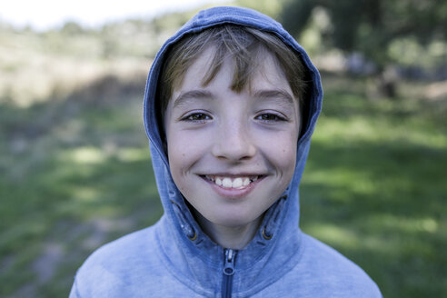 Portrait of laughing boy wearing blue hooded jacket - KMKF00214