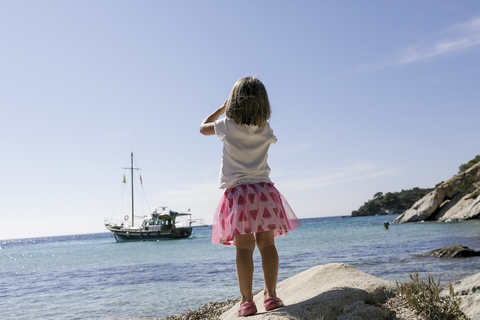 Back view of little girl with binoculars watching boat stock photo