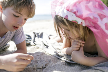 Junge und seine kleine Schwester liegen am Strand - KMKF00226