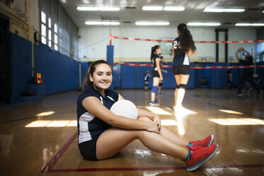 Porträt eines Mädchens, das einen Volleyball hält und auf dem Boden sitzt - CAVF45255