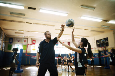 Männlicher Trainer unterrichtet ein Mädchen im Teenageralter im Volleyball - CAVF45274