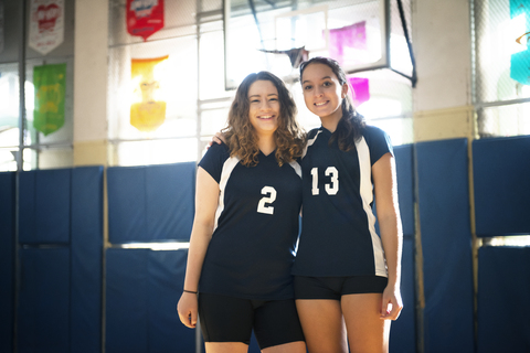 Porträt von lächelnden Teenager-Mädchen, die im Volleyballfeld stehen, lizenzfreies Stockfoto