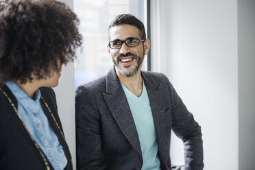 Happy businessman talking to colleague in office - CAVF45310