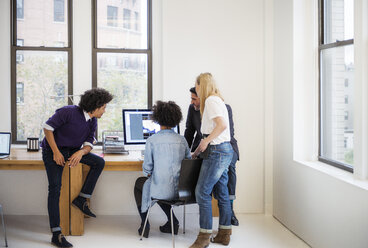 Colleagues working on computer in creative office - CAVF45330