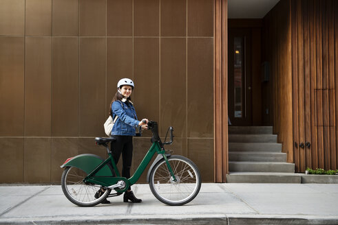 Frau mit Fahrrad auf dem Gehweg vor einem Gebäude - CAVF45350