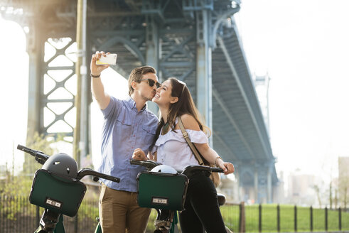 Pärchen küsst sich beim Selfie mit Fahrrädern vor der Manhattan Bridge - CAVF45357