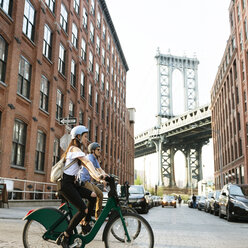 Paar radelt auf der Straße bei Gebäuden in der Stadt gegen die Manhattan-Brücke - CAVF45368