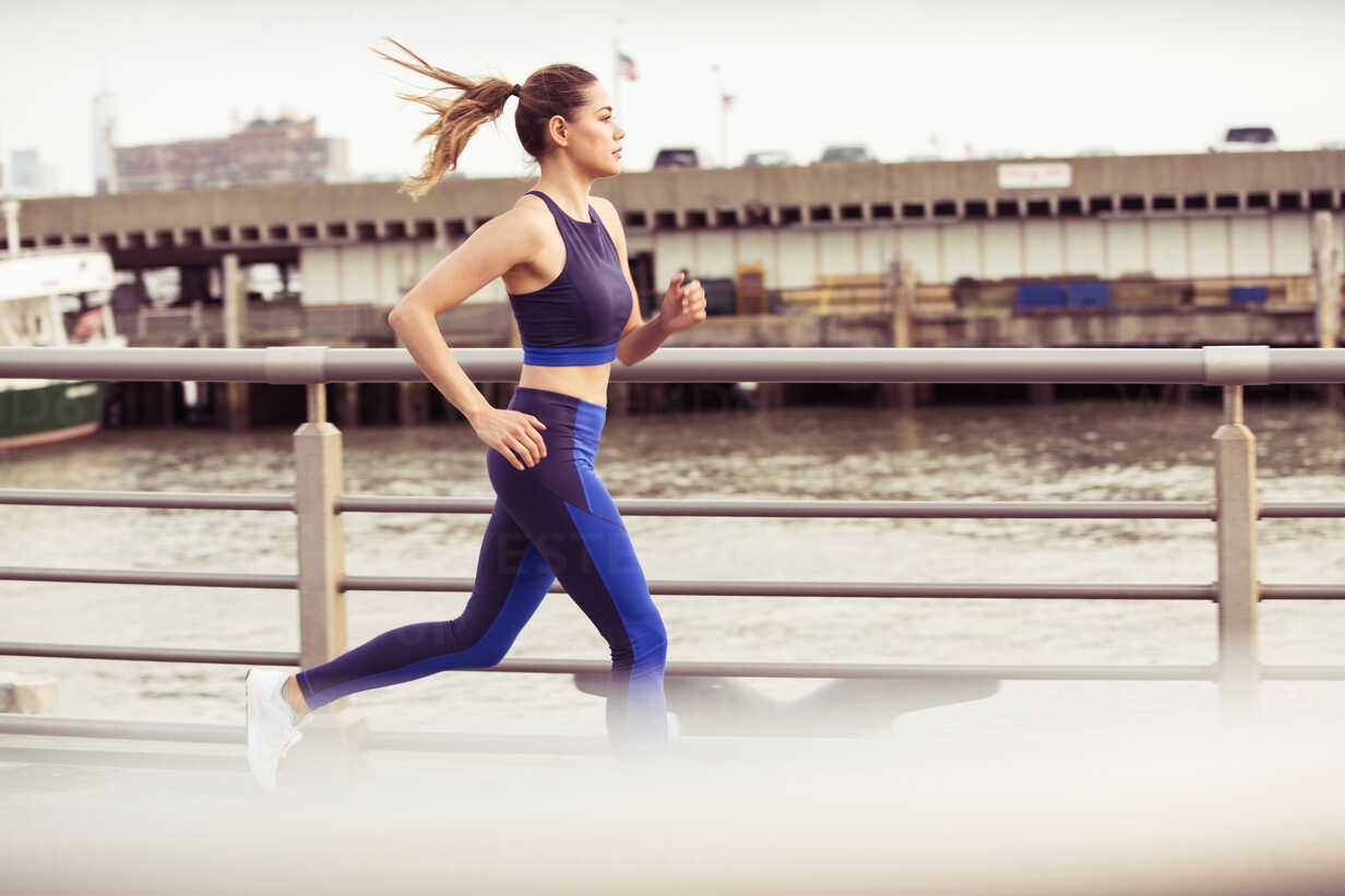 Woman jogging on bridge in city stock photo