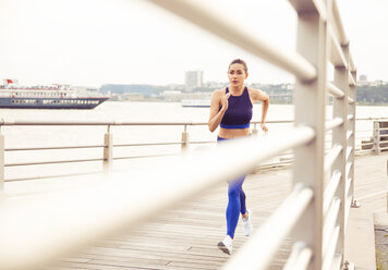 Woman running while exercising on bridge in city - CAVF45399