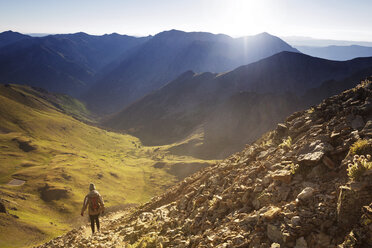 Rear view of woman walking on mountains against clear sky - CAVF45445