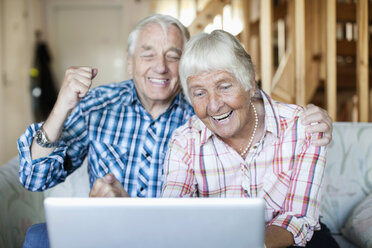 Aufgeregtes älteres Paar mit Blick auf den Laptop - MASF06586