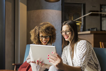 Glückliche Geschäftsfrauen mit Tablet-Computer in der Hotellobby - CAVF45448