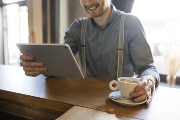 Mittelteil eines Geschäftsmannes, der einen Tablet-Computer am Schalter eines Hotels benutzt - CAVF45458