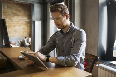 Businessman using tablet computer at counter in hotel - CAVF45461